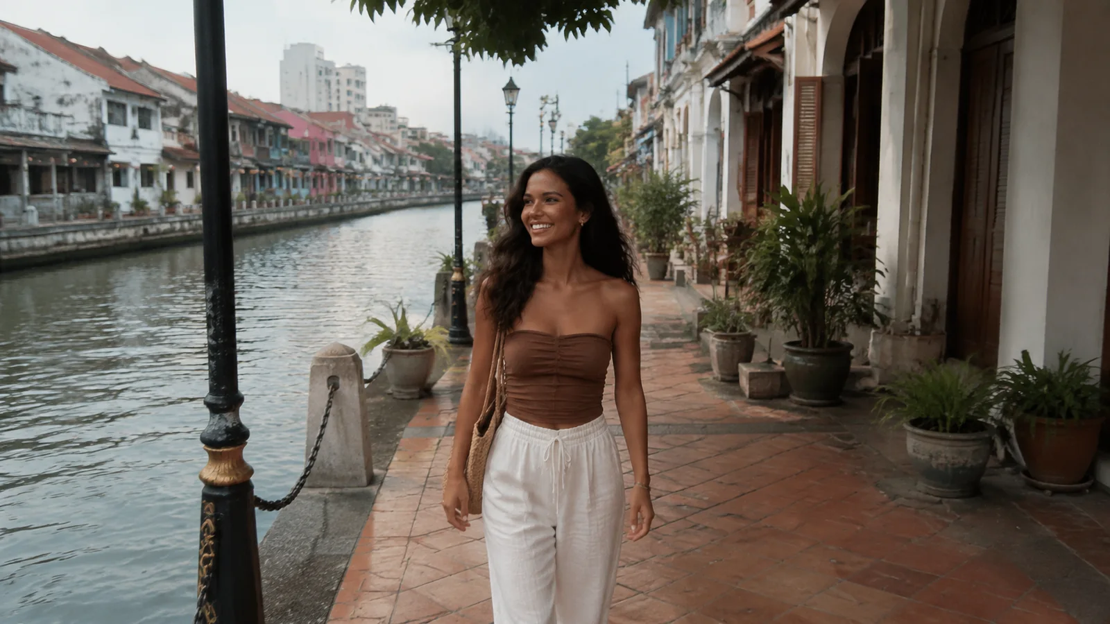 Woman walks along a riverside promenade lined with old buildings.