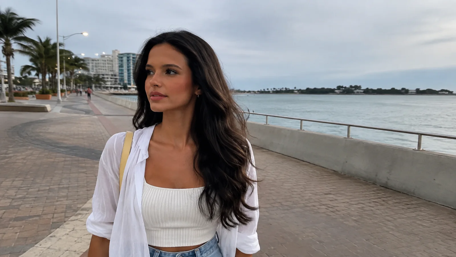 Woman strolling along a paved coastal promenade.