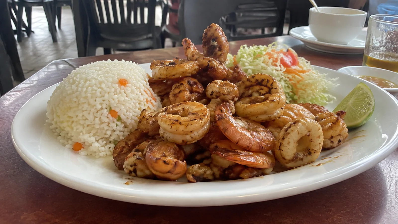 Plate of seafood, rice and salad with a lime wedge.