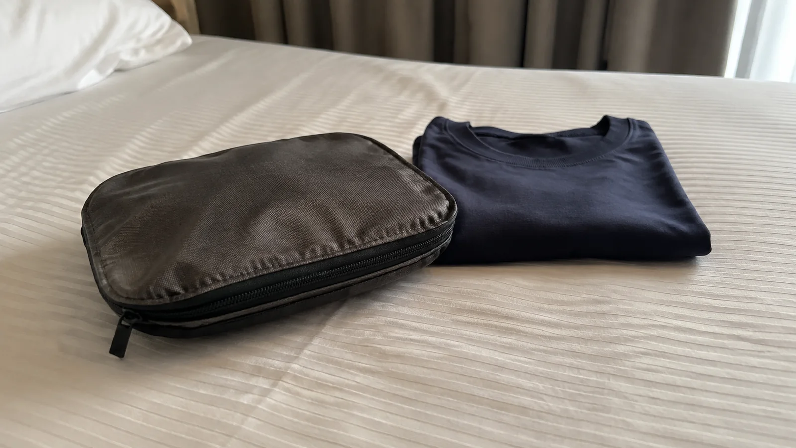 Toiletry bag and folded dark shirt on a cabin bed.