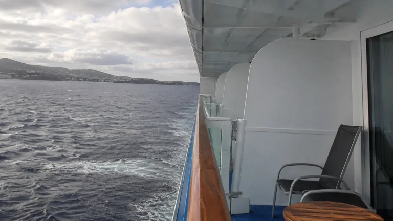 Empty cruise ship balcony with two chairs overlooking the sea