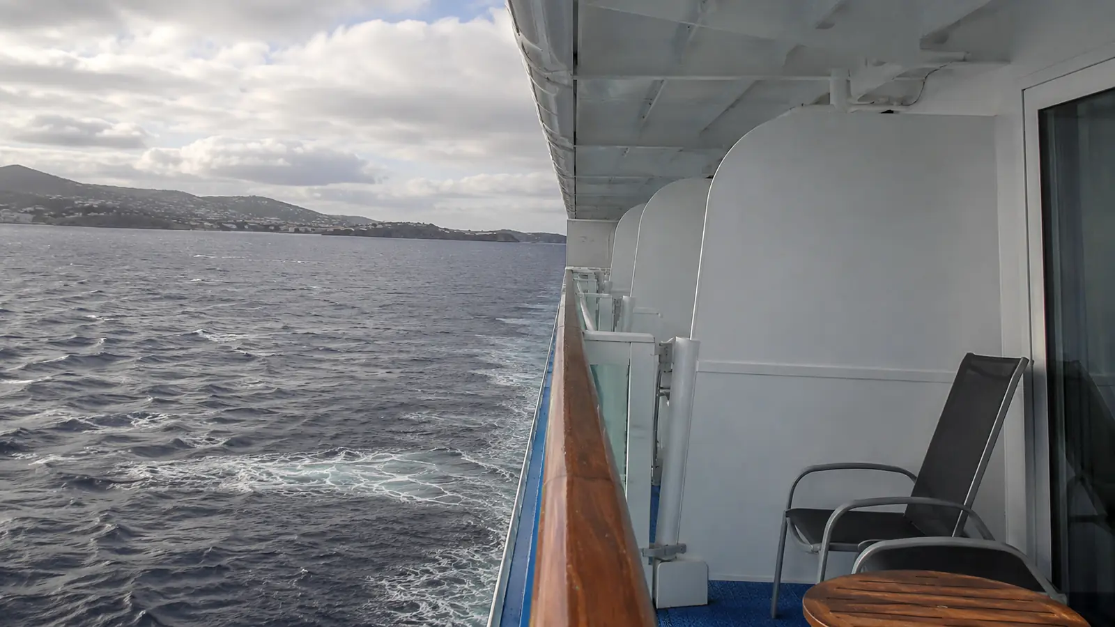 Empty cruise ship balcony with two chairs overlooking the sea