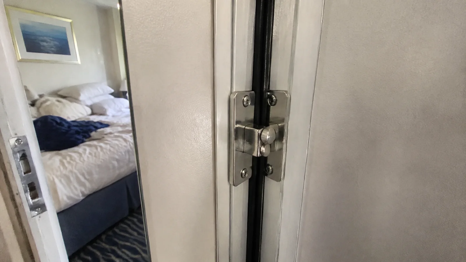 Close-up of a connecting-door hinge beside a cabin doorway.