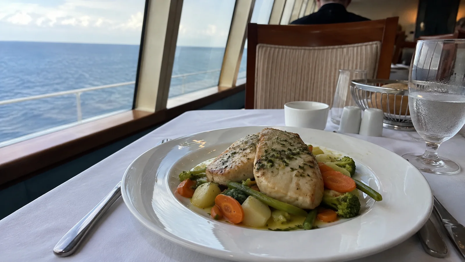 Fish and vegetables served at a window table overlooking the ocean.