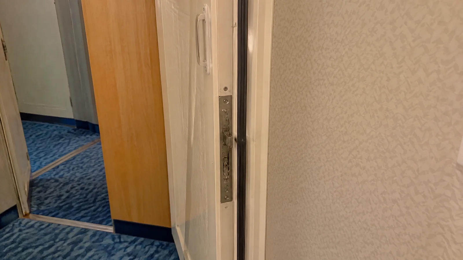 Close-up of an open connecting door between carpeted cruise cabins