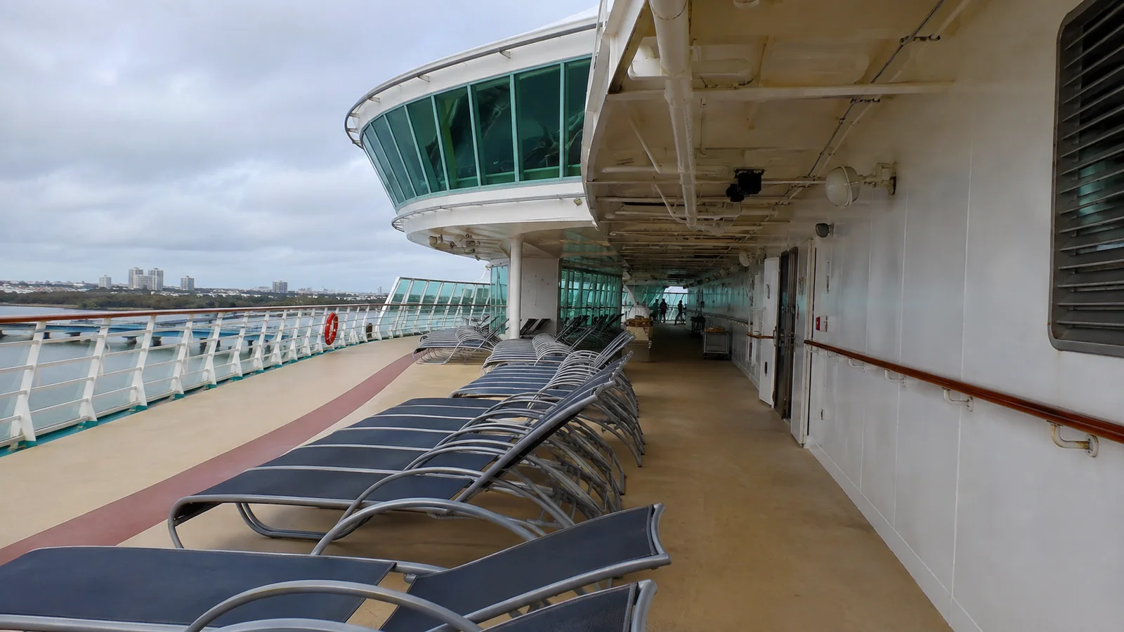 Empty lounge chairs beneath the projecting bridge of a cruise ship