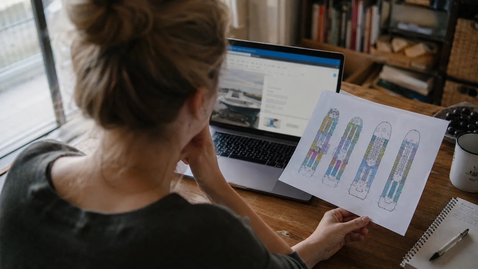 Woman holding a printed cruise ship deck plan beside a laptop