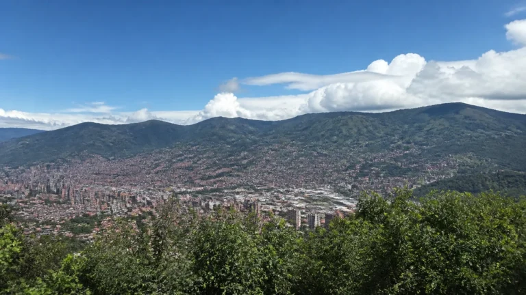 Dense city spreads across a mountain valley beneath blue skies.