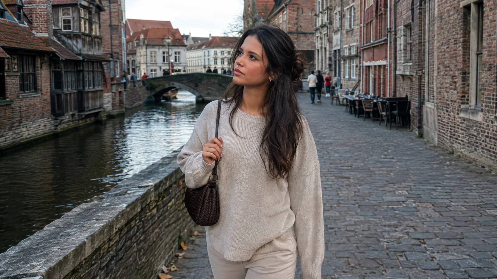 Woman walking along a cobbled canal-side street.