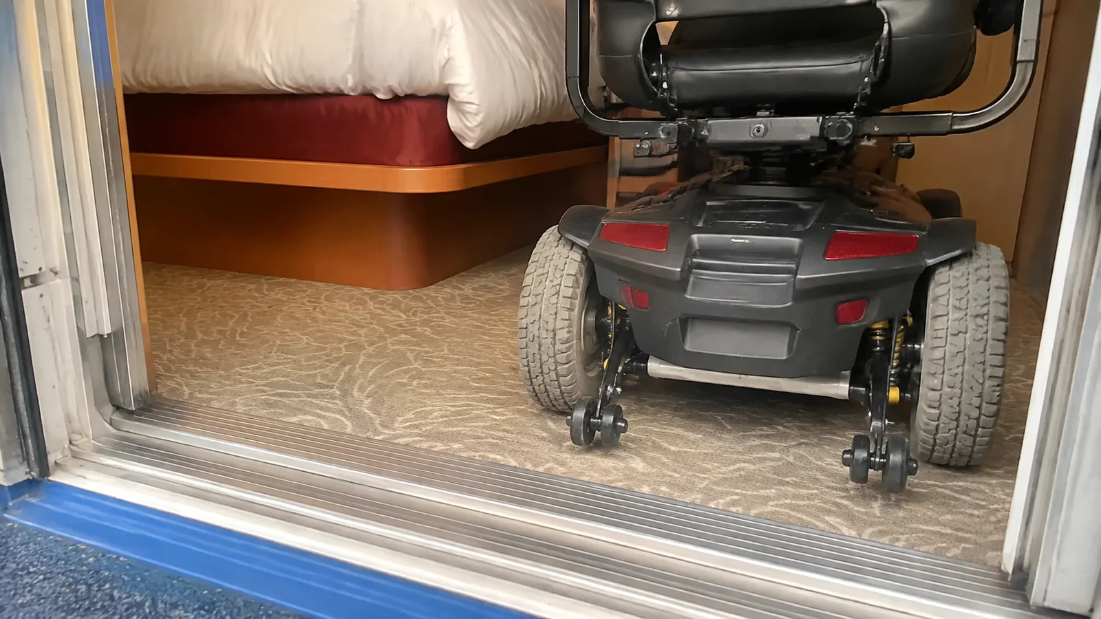 Rear wheels of a mobility scooter beside a cabin doorway threshold.