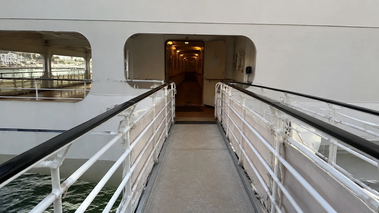 Sloping gangway with metal handrails leading into a ship entrance.