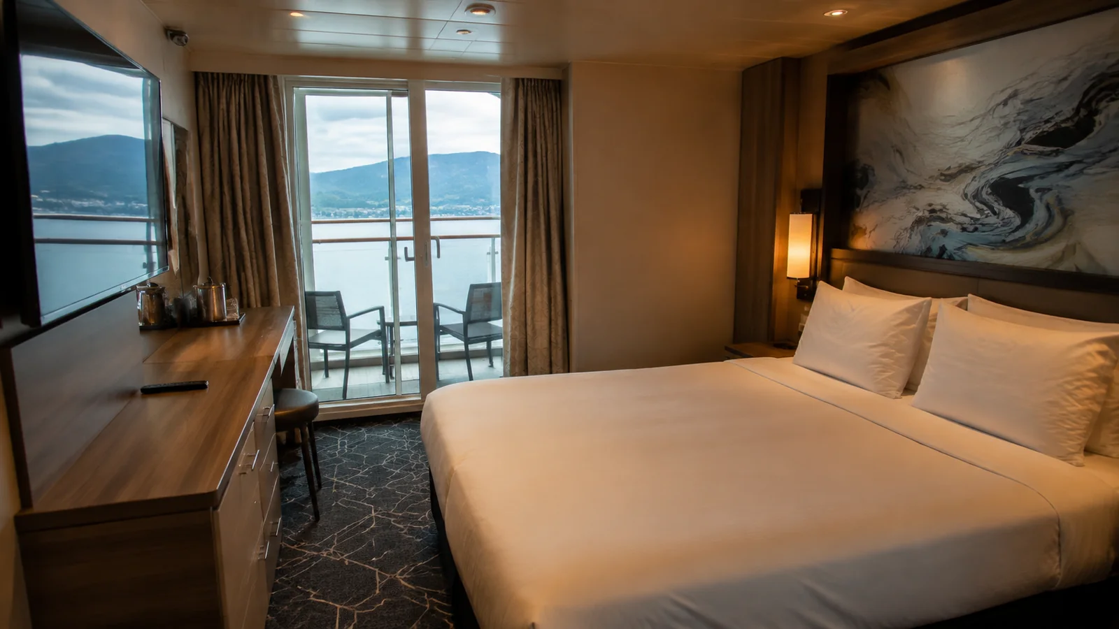 Double bed faces glass balcony doors in a modern stateroom.