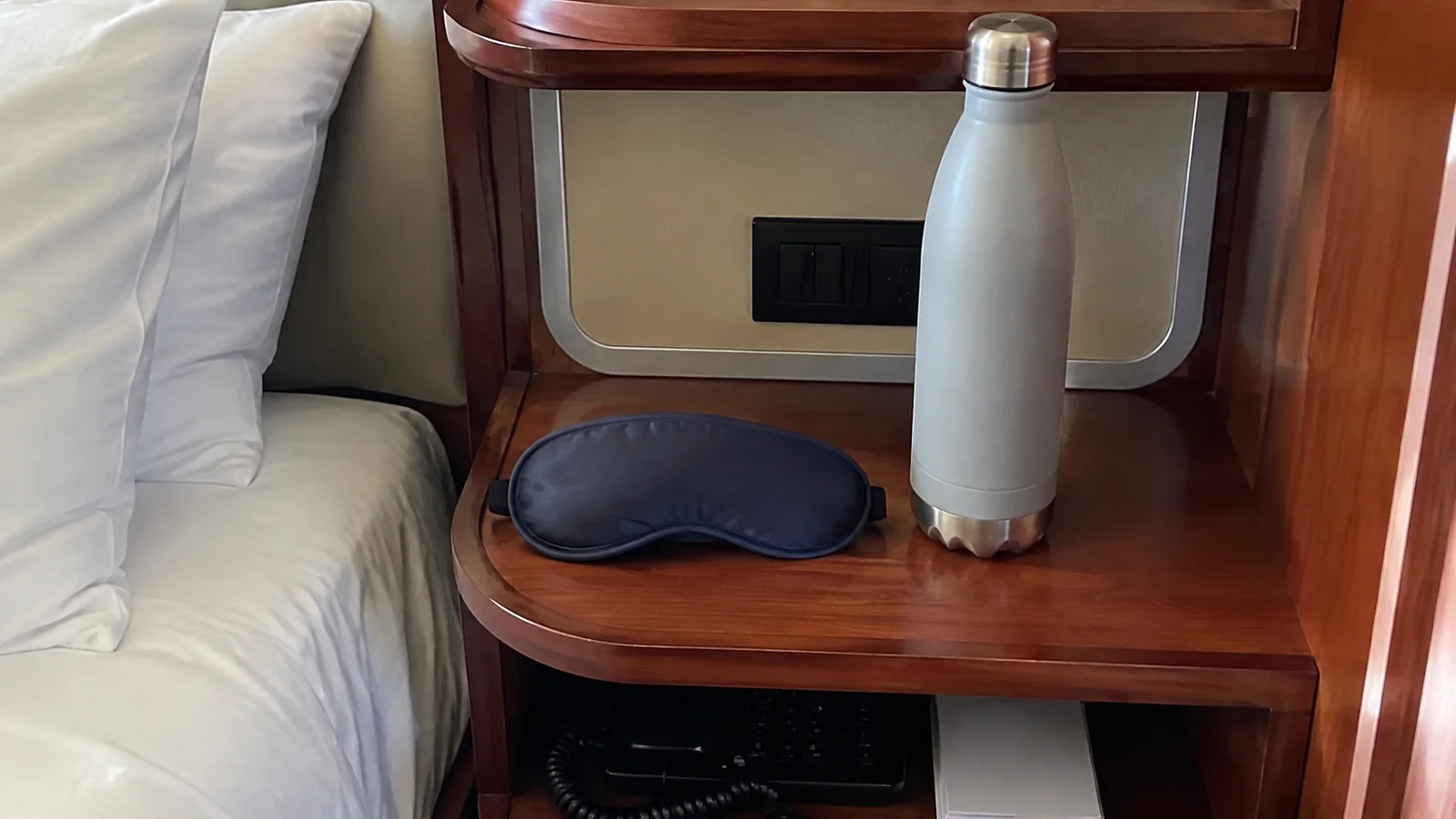 Sleep mask and reusable bottle sit on a bedside table.