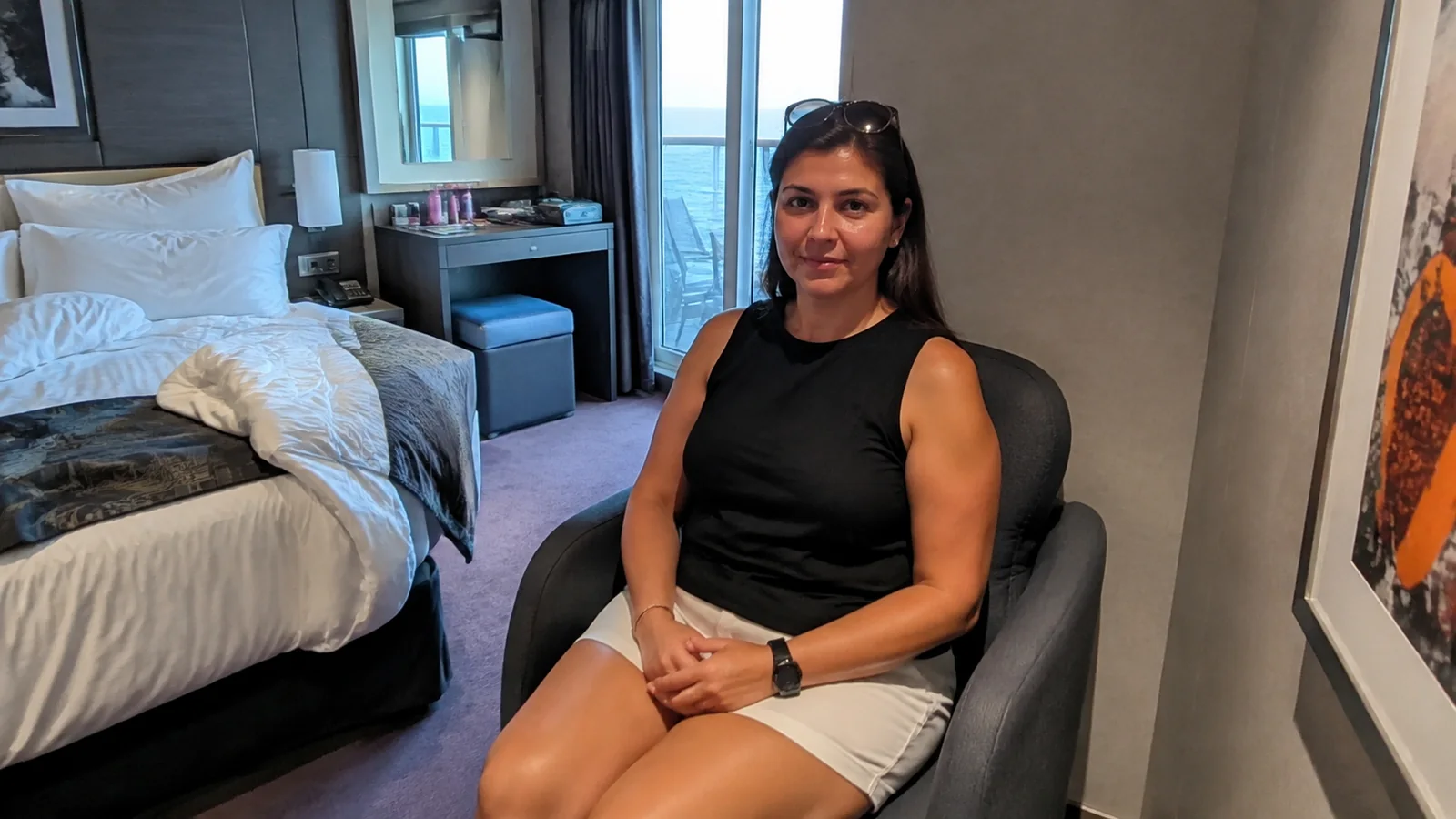 Woman sits with hands folded in a stateroom chair.