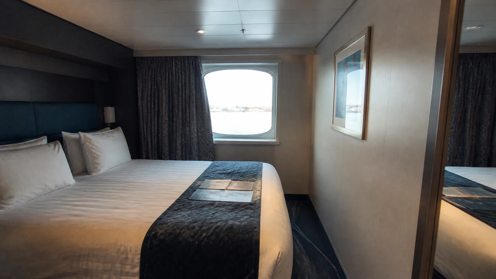 Cruise cabin with a double bed, blue runner, and window