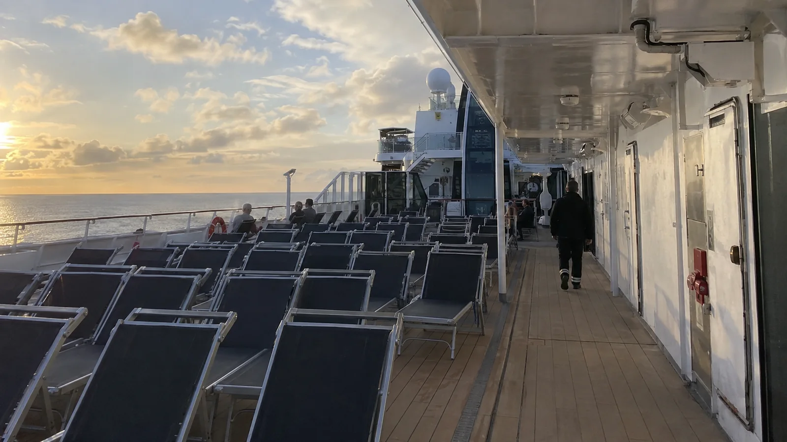 Rows of lounge chairs on a cruise ship promenade at sunset