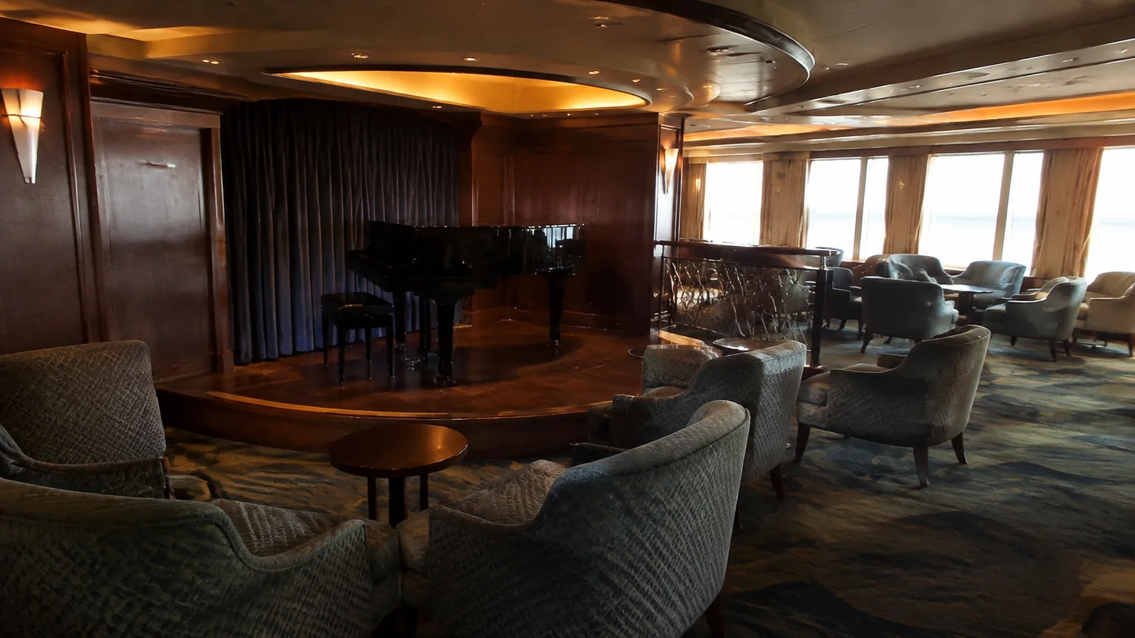 Piano and seating area in a lounge with wood-paneled walls.