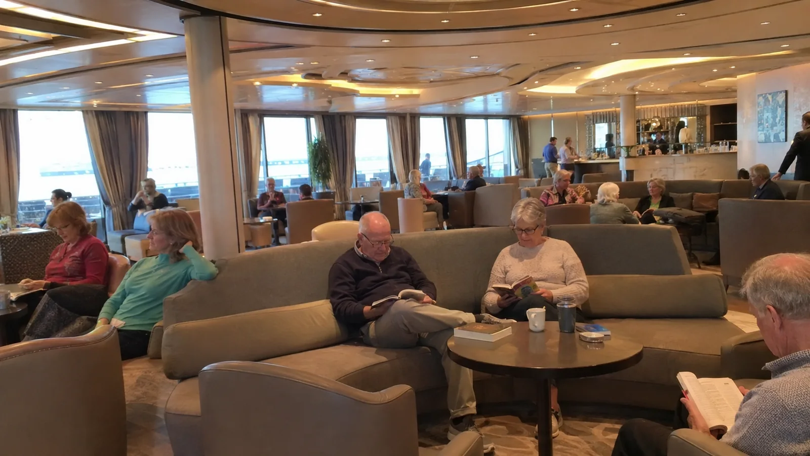 Passengers relaxing on sofas in a spacious ship lounge.