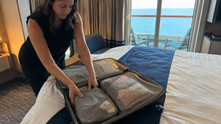 Woman arranges packing cubes in an open suitcase on a cabin bed.