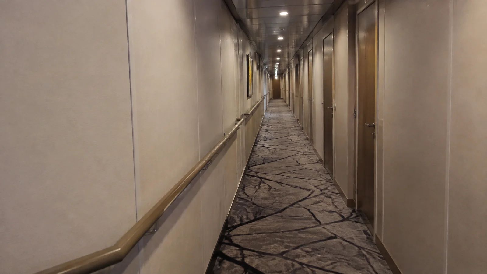Long empty ship corridor with cream walls and patterned carpet.