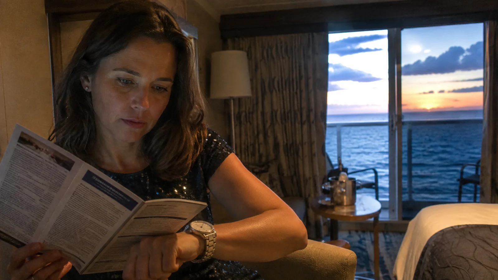 Passenger checking her watch while reading a program in a cabin.
