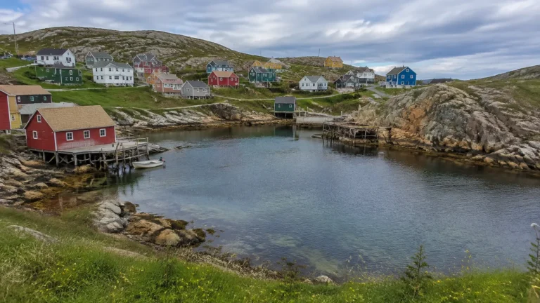 Colorful houses surround a rocky sheltered harbor beneath low hills.