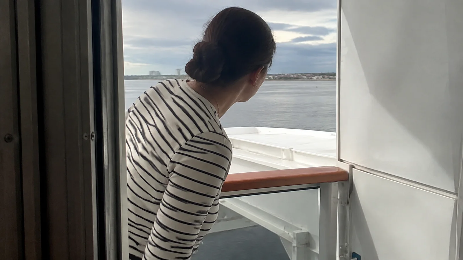Woman leaning out of a balcony doorway to see past an obstruction