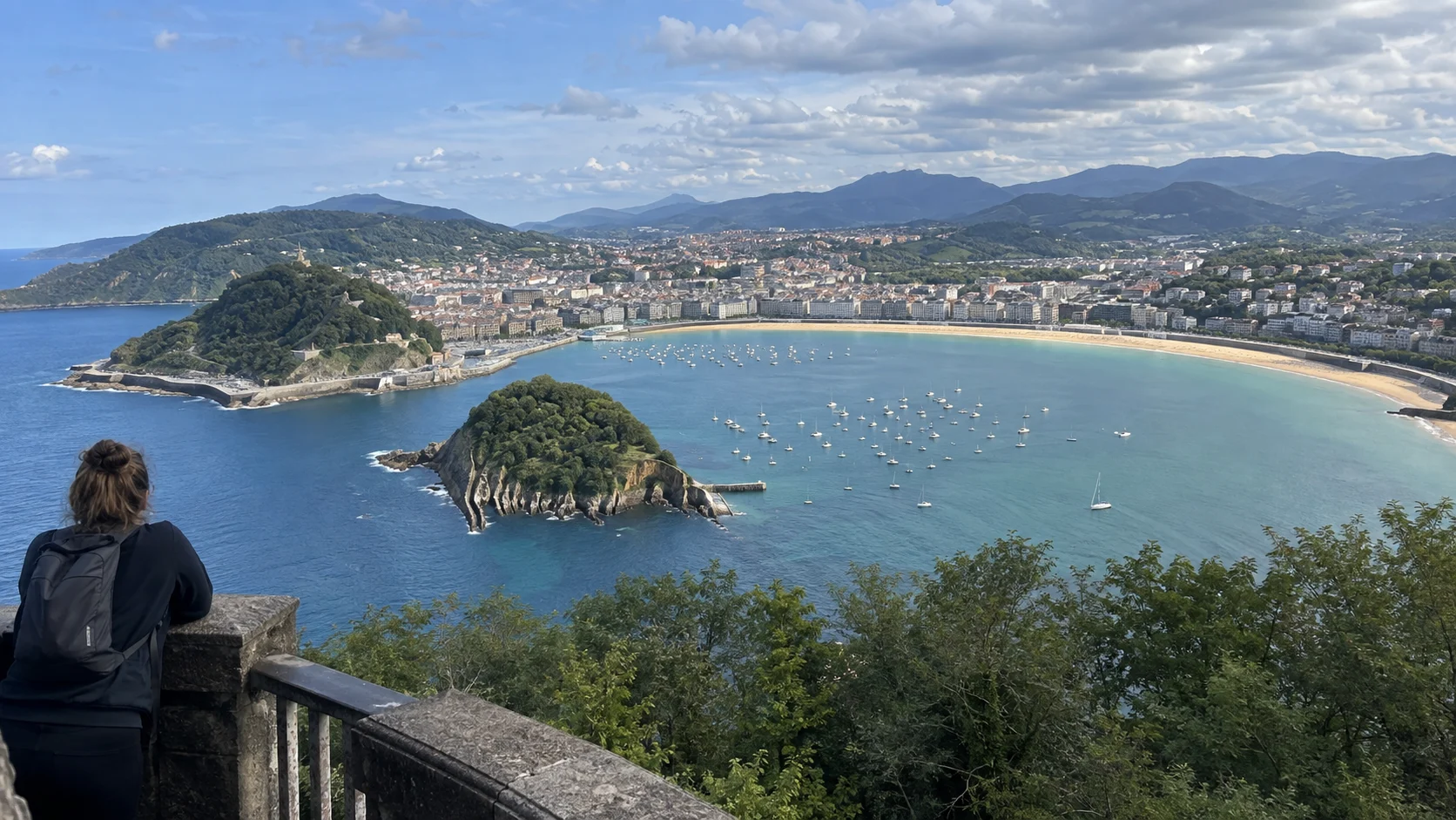 Traveler overlooking La Concha Bay, Santa Clara Island, and San Sebastián from Monte Igueldo.