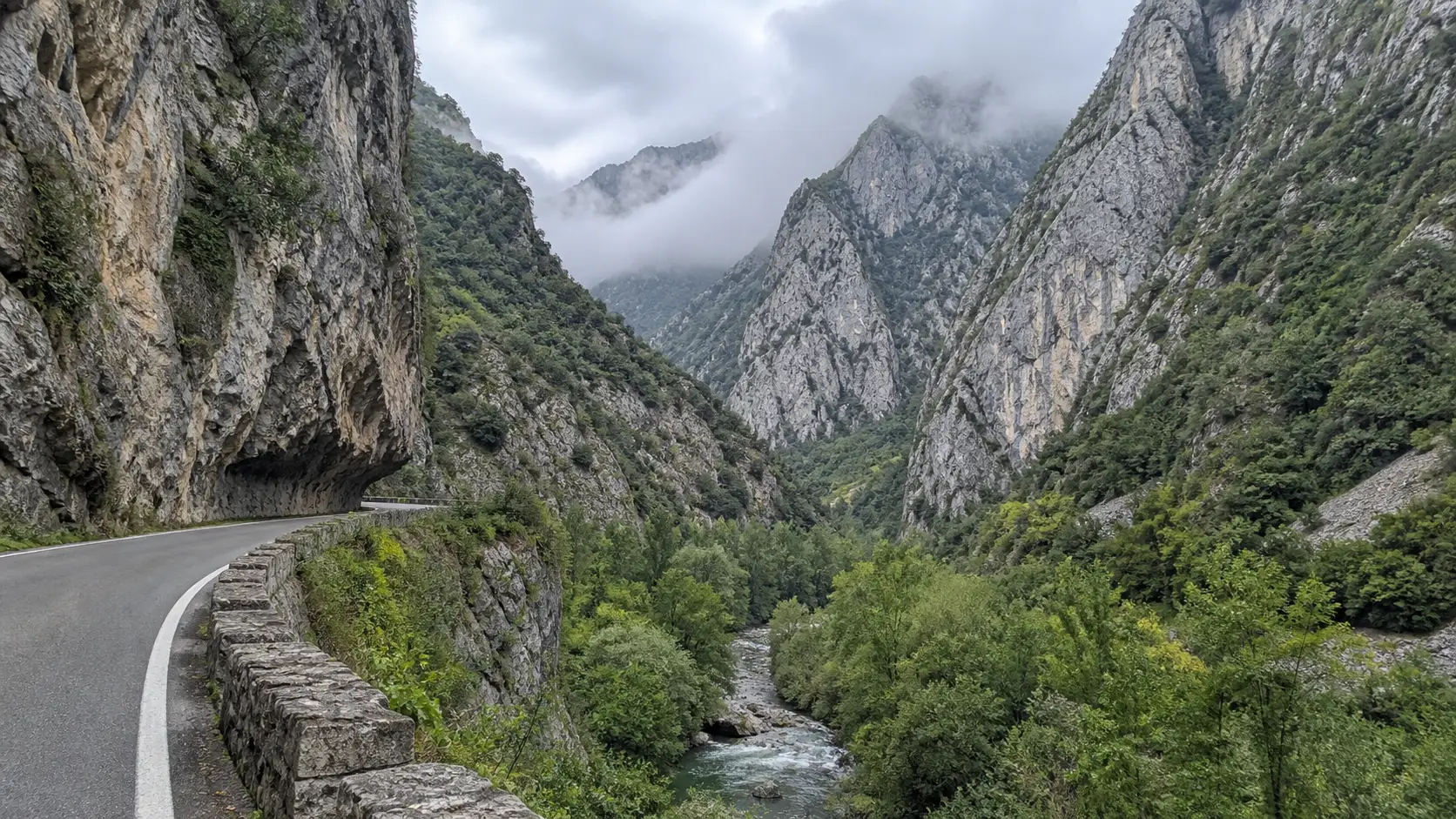 Narrow road following the river beneath limestone walls in the Hermida Gorge.