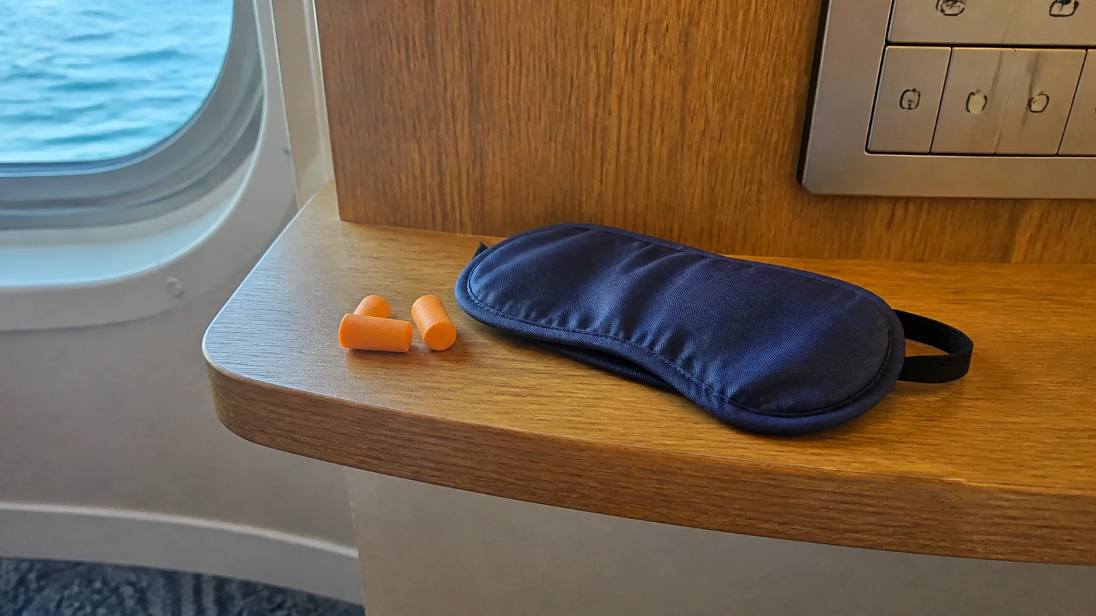 Blue sleep mask and orange earplugs lie beneath electrical outlets.