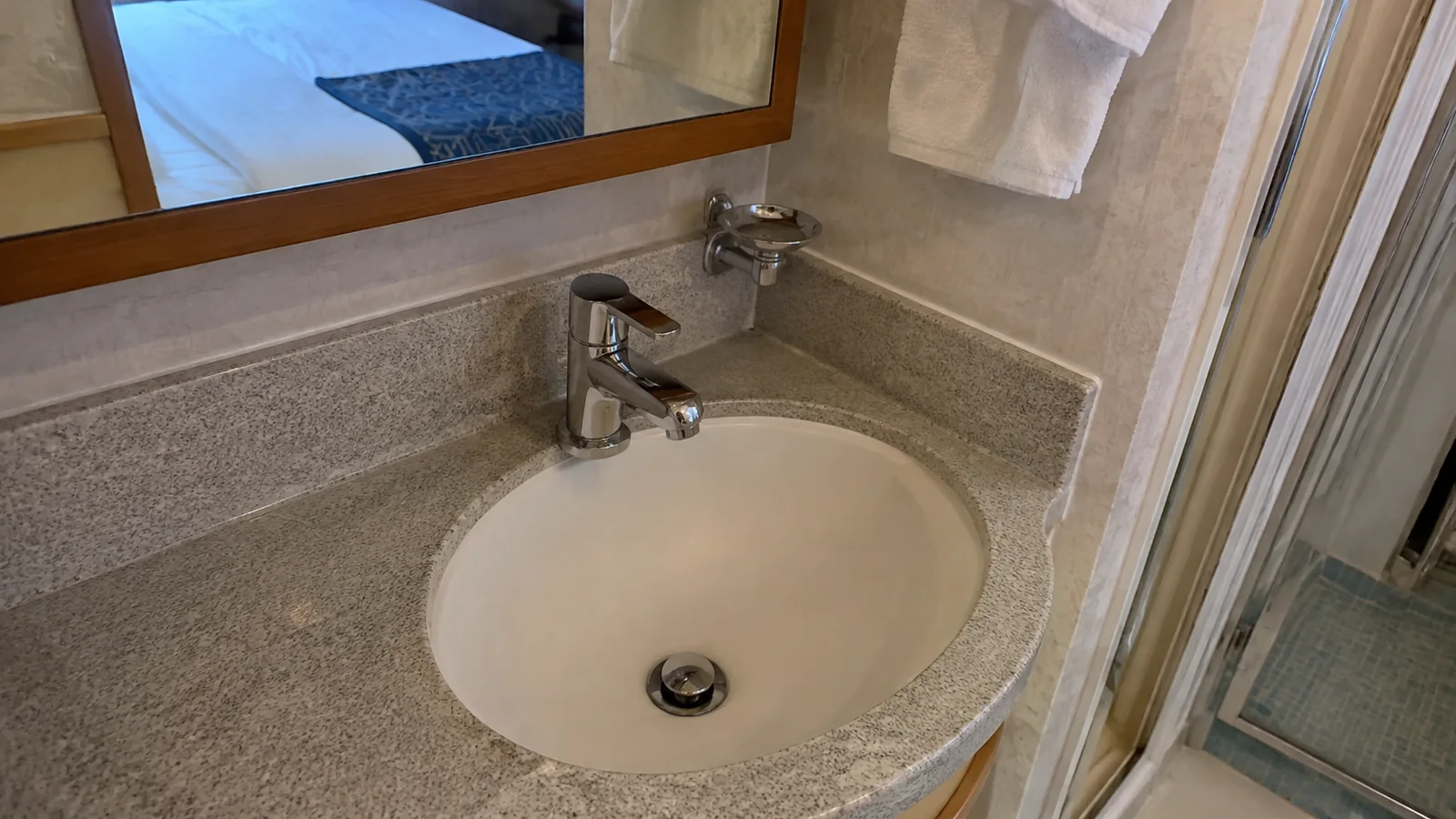 Close view of a bathroom sink, faucet, and shower enclosure.