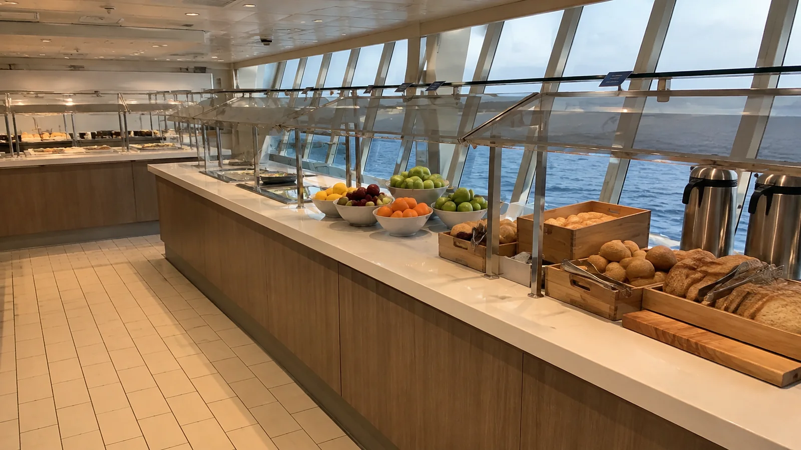 Long buffet counter displays bread and fruit beneath glass screens.