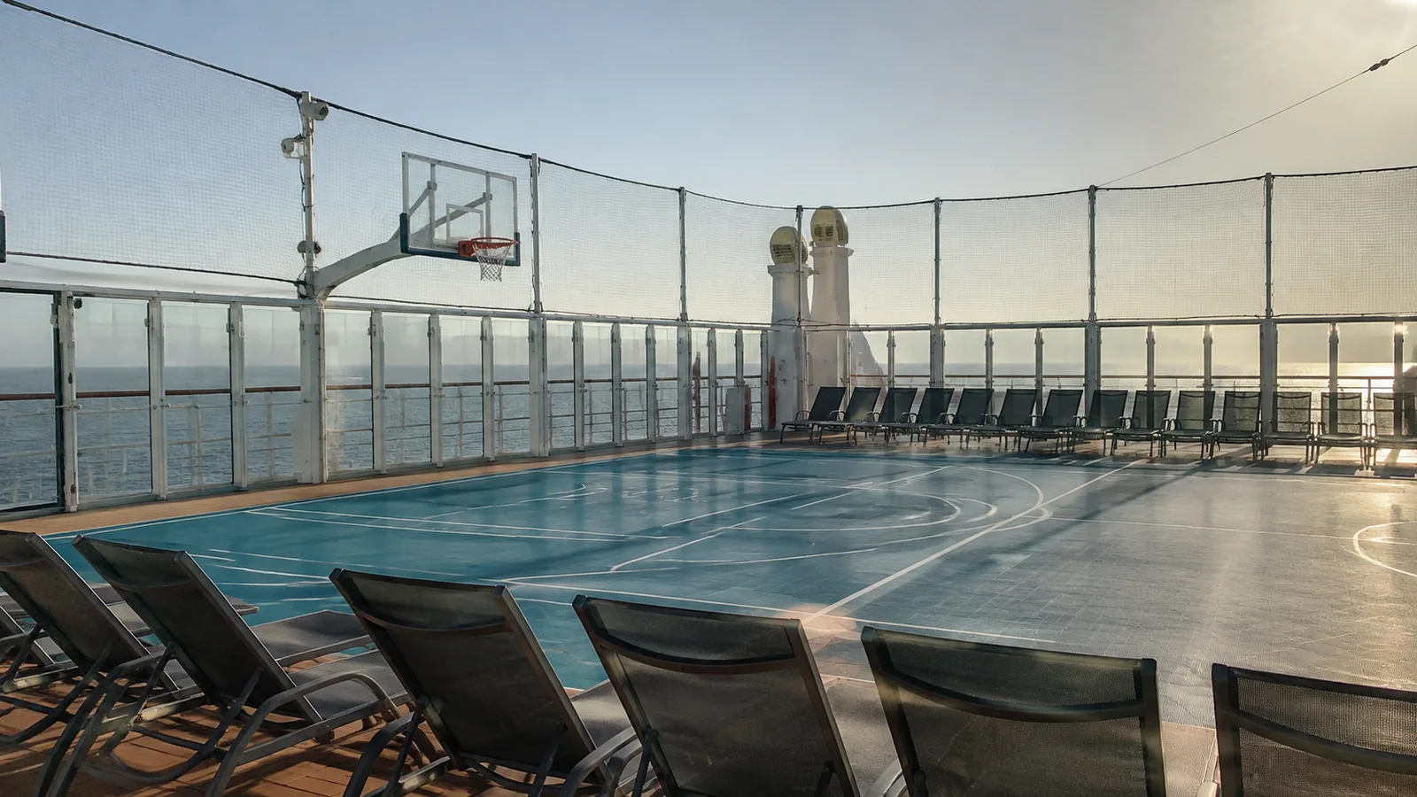 Basketball court surrounded by safety netting on a ship's upper deck.