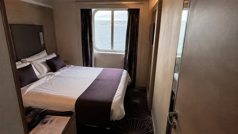 Cruise cabin with a double bed and a narrow ocean-view window