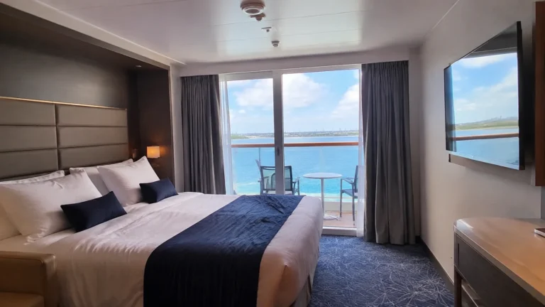 Double bed and television in a cabin with an ocean-view balcony.