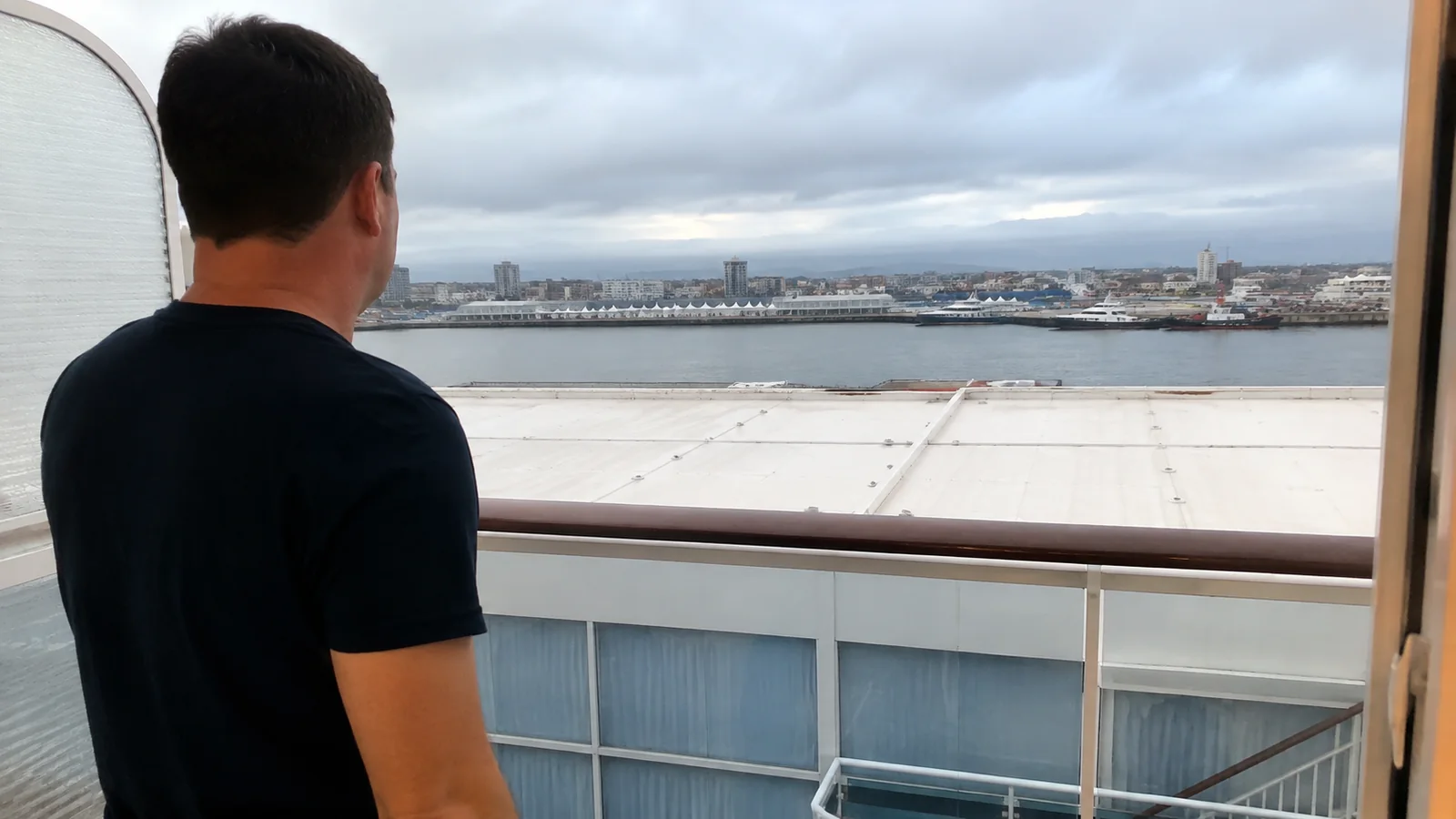Passenger looking from a balcony over the roof of a lower ship deck.