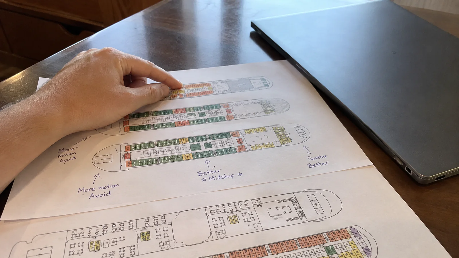 Hand pointing at a printed cruise ship deck plan.