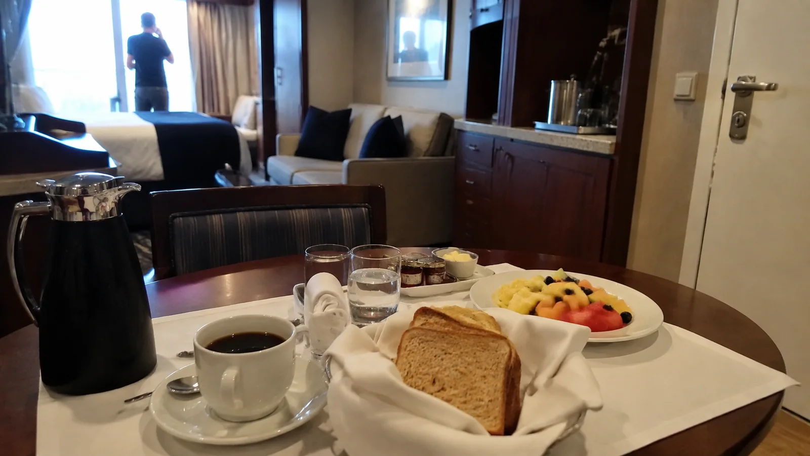 Breakfast plates and coffee fill a table inside a cruise suite.