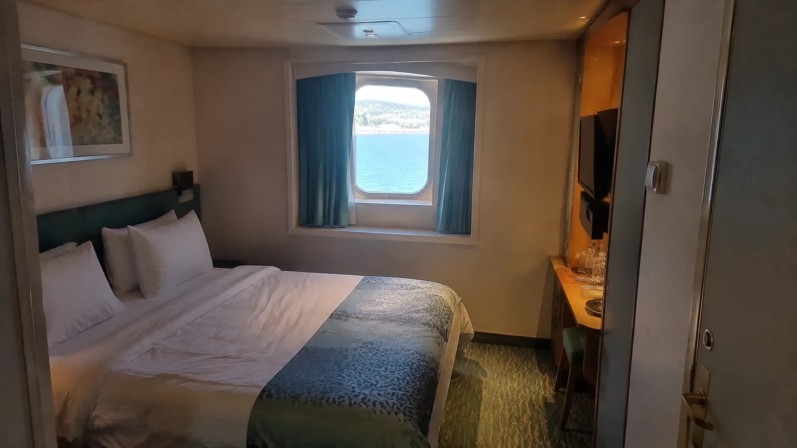 Cruise cabin with a double bed and curtained ocean-view window