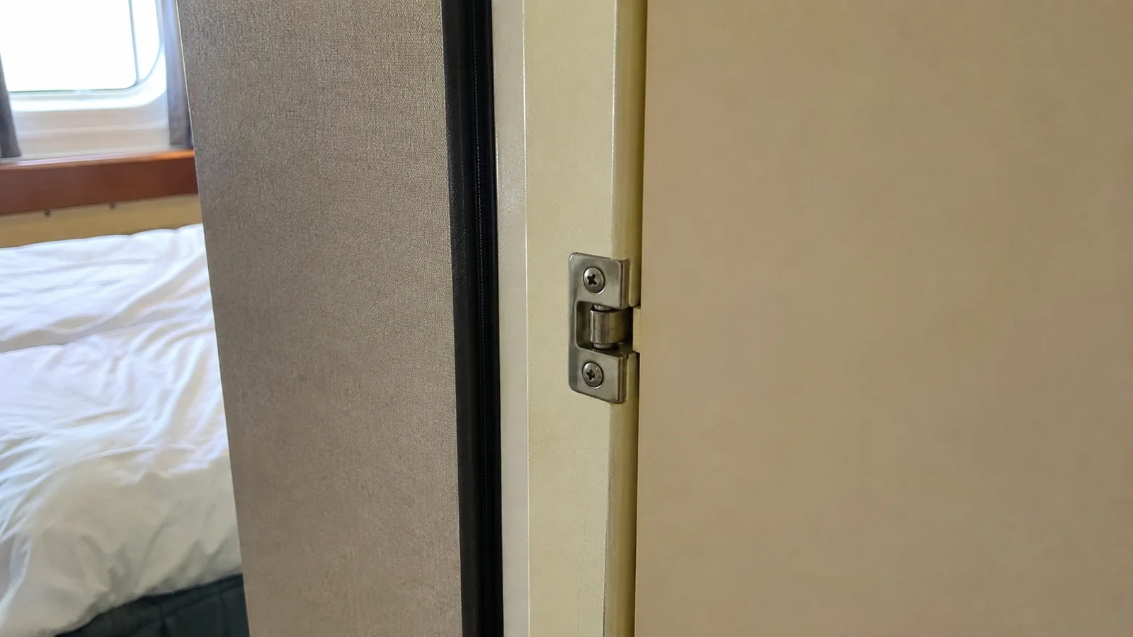 Close-up of a connecting door latch beside a cruise cabin bed