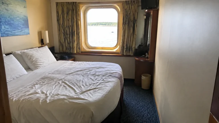 Cruise cabin with a double bed and a large curtained window