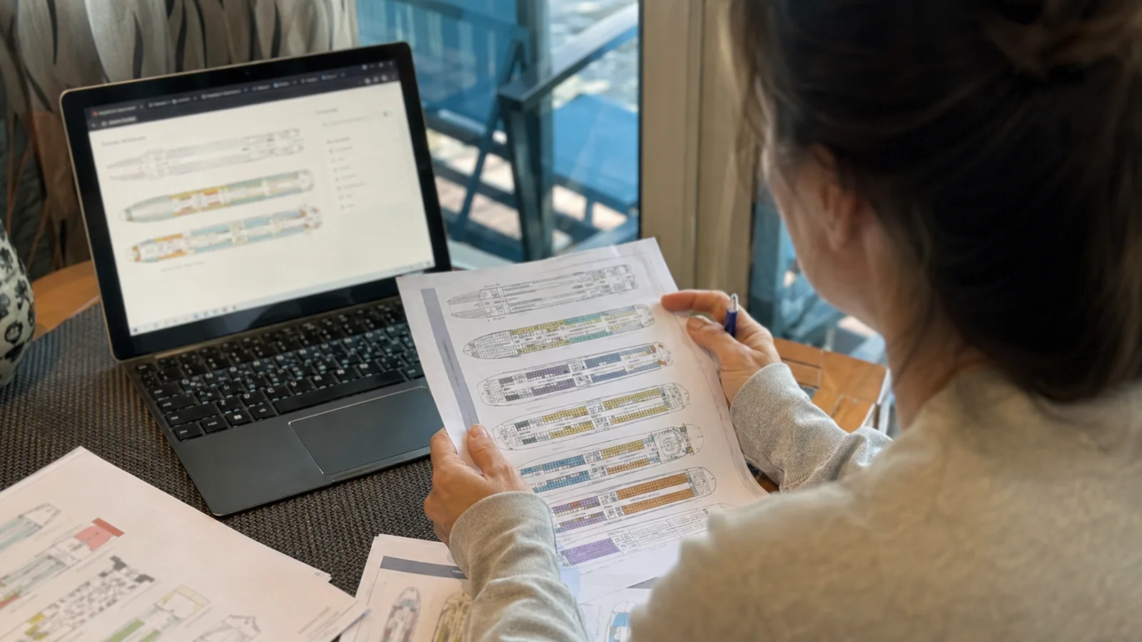 Woman comparing a printed cruise ship deck plan with a laptop