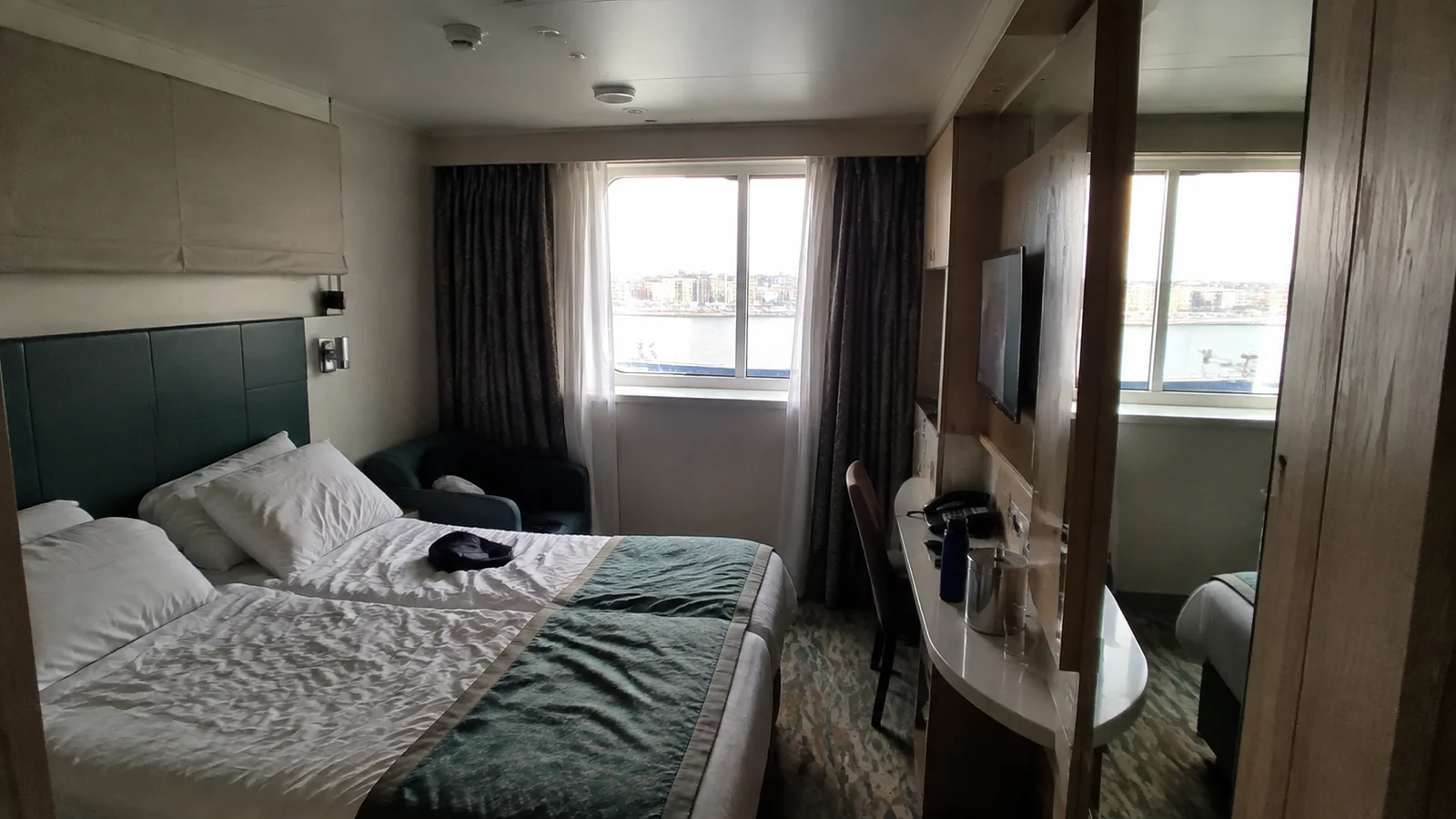 Cruise cabin with a double bed, mirrored wardrobe, and window
