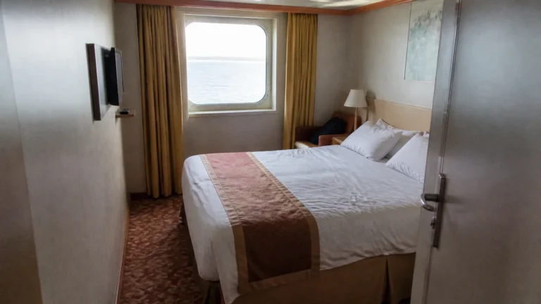 Cruise cabin with a double bed and curtained ocean-view window