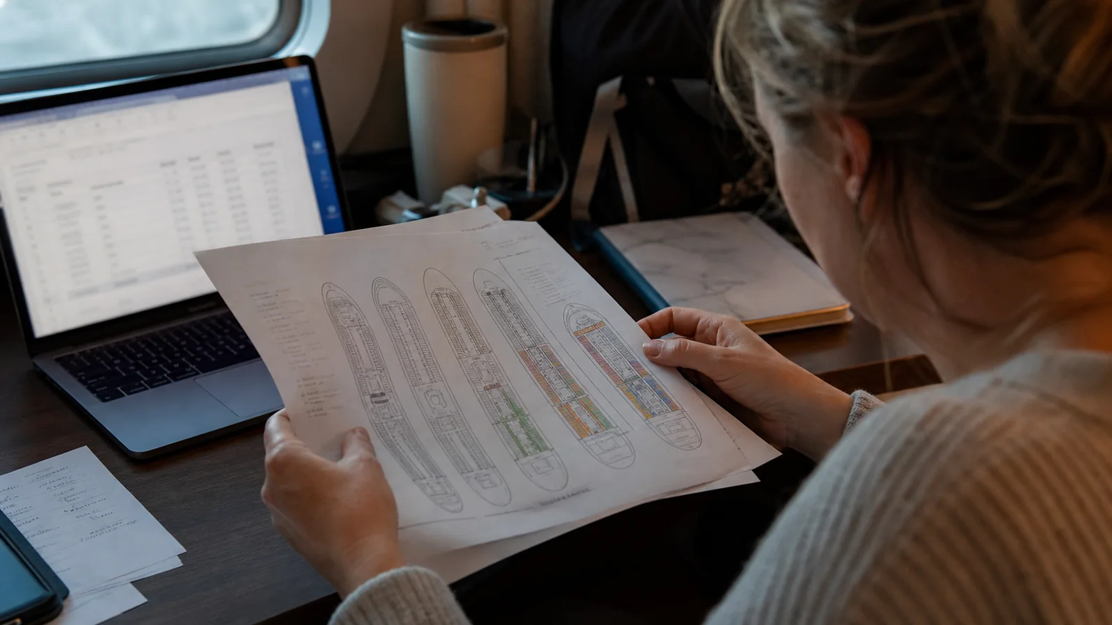 Woman reviewing a printed cruise ship deck plan beside a laptop