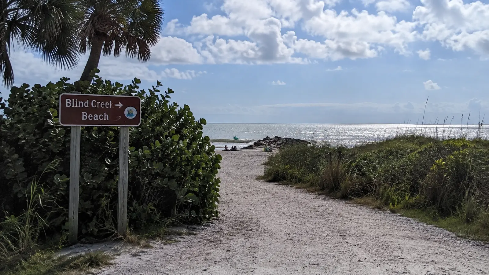 Blind Creek Beach sign beside a sandy path through coastal dunes