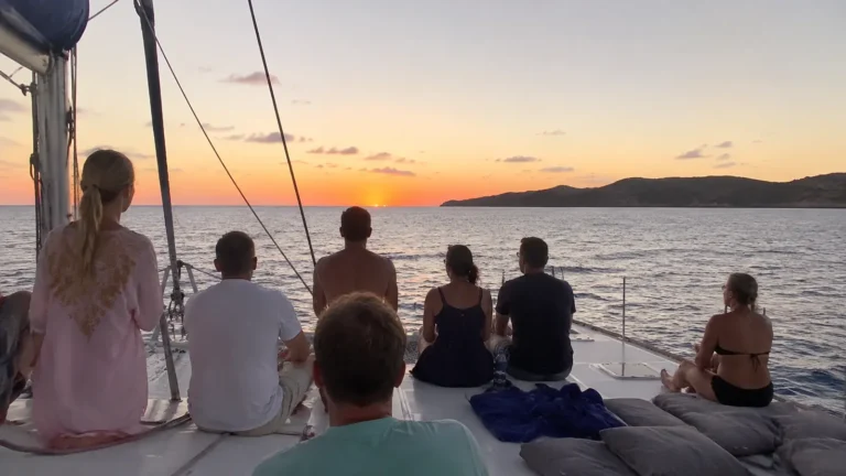 Passengers seated on an open cruise ship deck watching the sunset