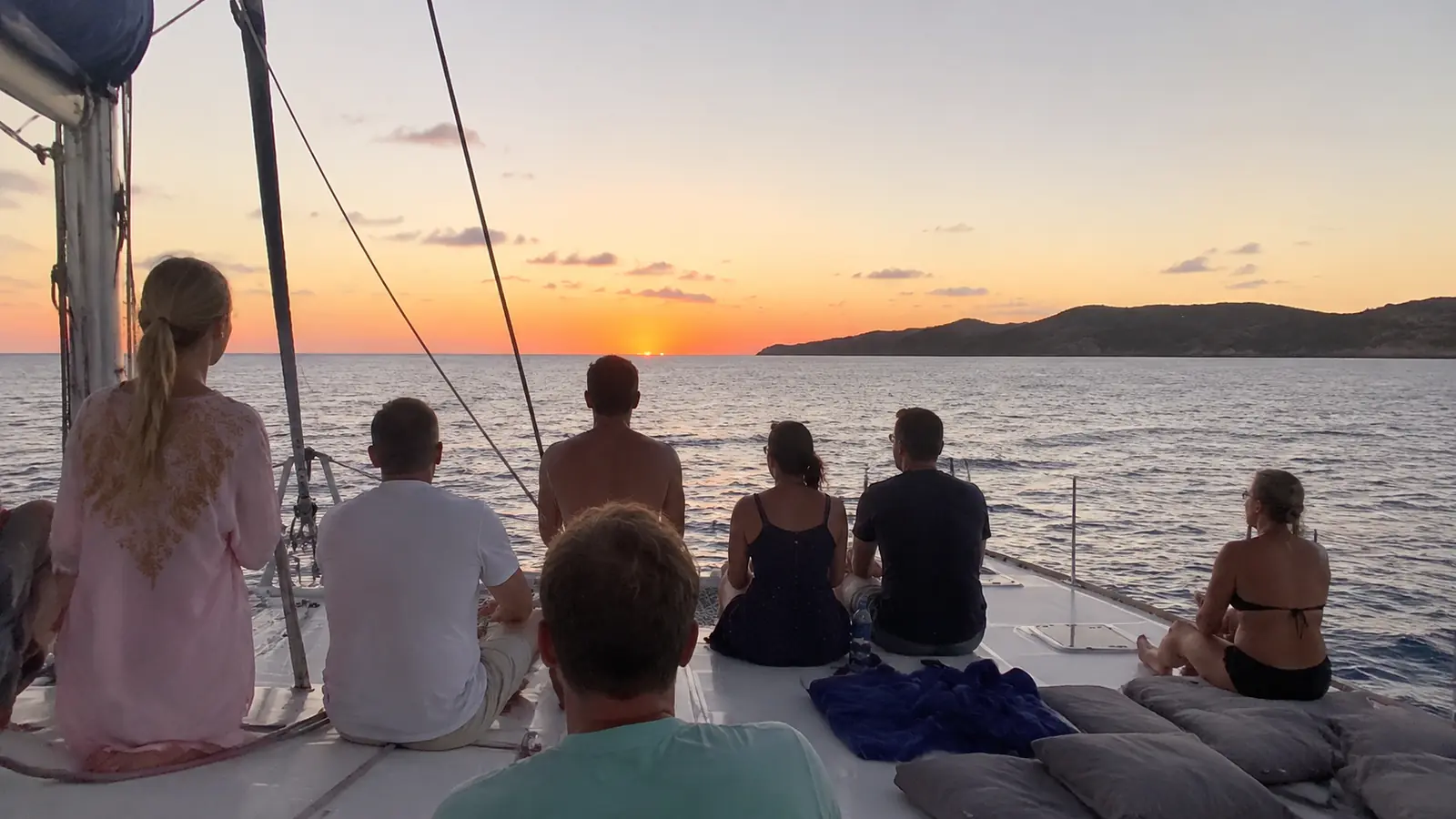 Passengers seated on an open cruise ship deck watching the sunset