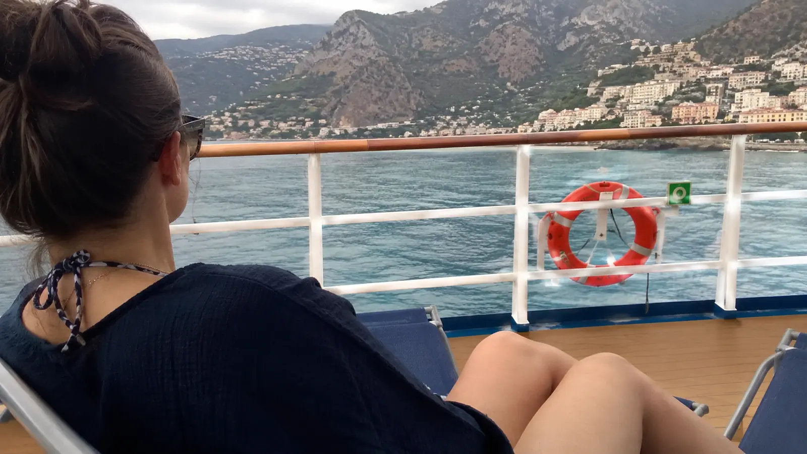 Woman seated on a cruise ship deck looking across a mountainous bay