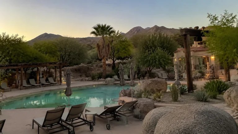 Desert resort pool surrounded by cactus and mountains